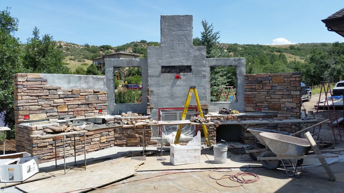 A large stone wall is being built in a backyard.