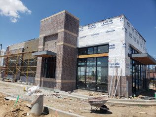 A building under construction with a wheelbarrow in front of it.