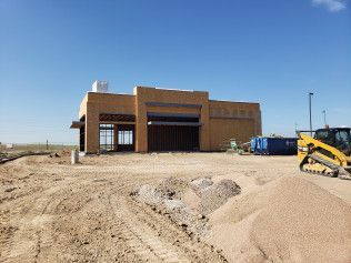 A yellow bulldozer is parked in front of a building under construction.
