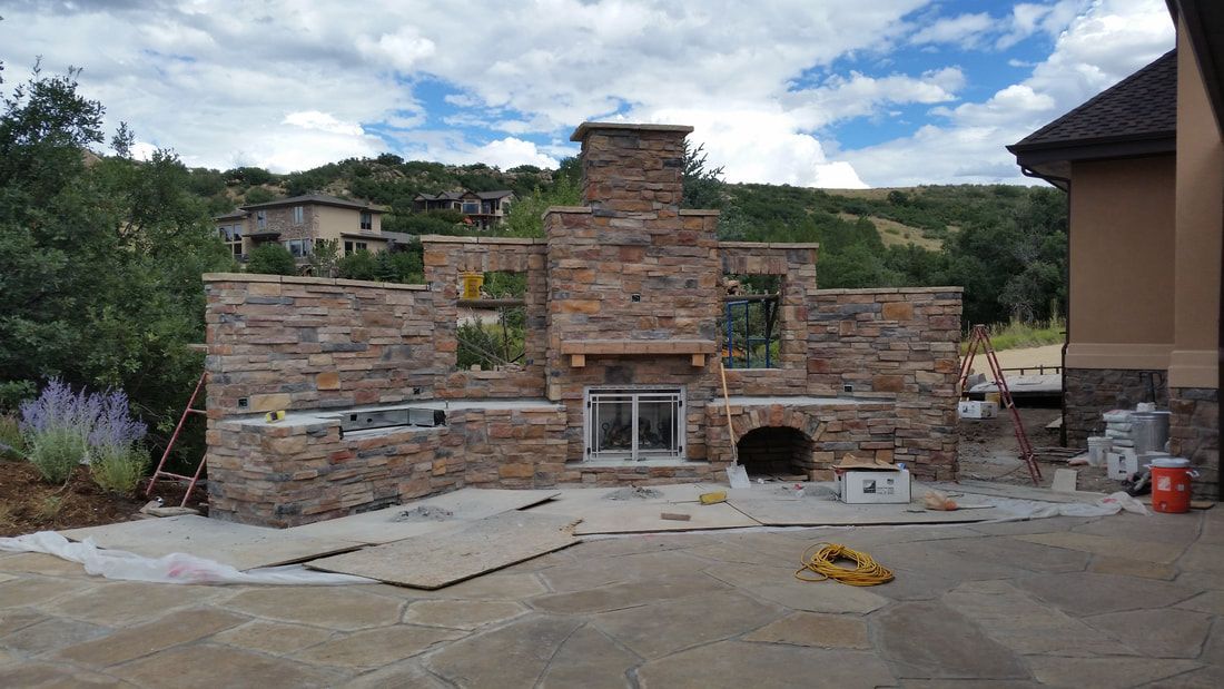 A stone fireplace is being built in the backyard of a house.