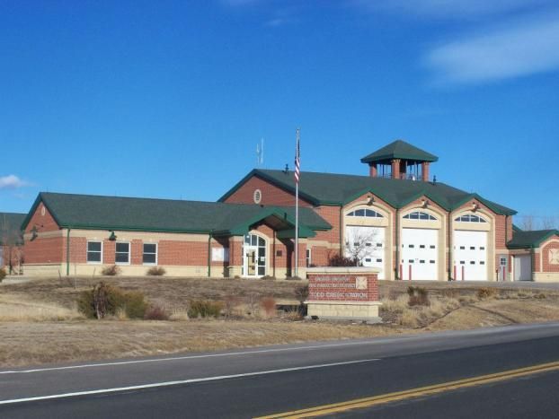 A large brick building with a green roof is next to a road
