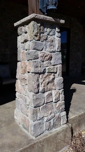 A stone pillar is sitting on top of a concrete porch.
