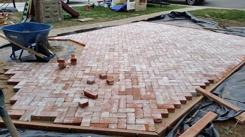 A wheelbarrow is sitting on top of a brick driveway being built.