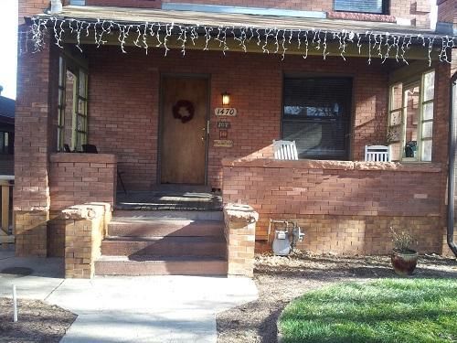 The front porch of a brick house with a wreath on the door