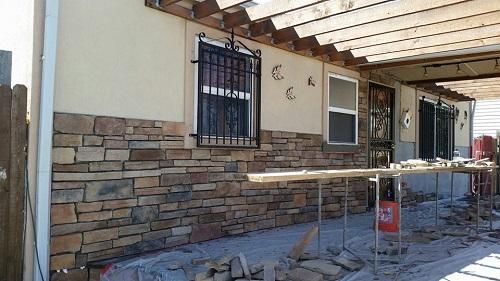 A stone wall is being built on the side of a house.