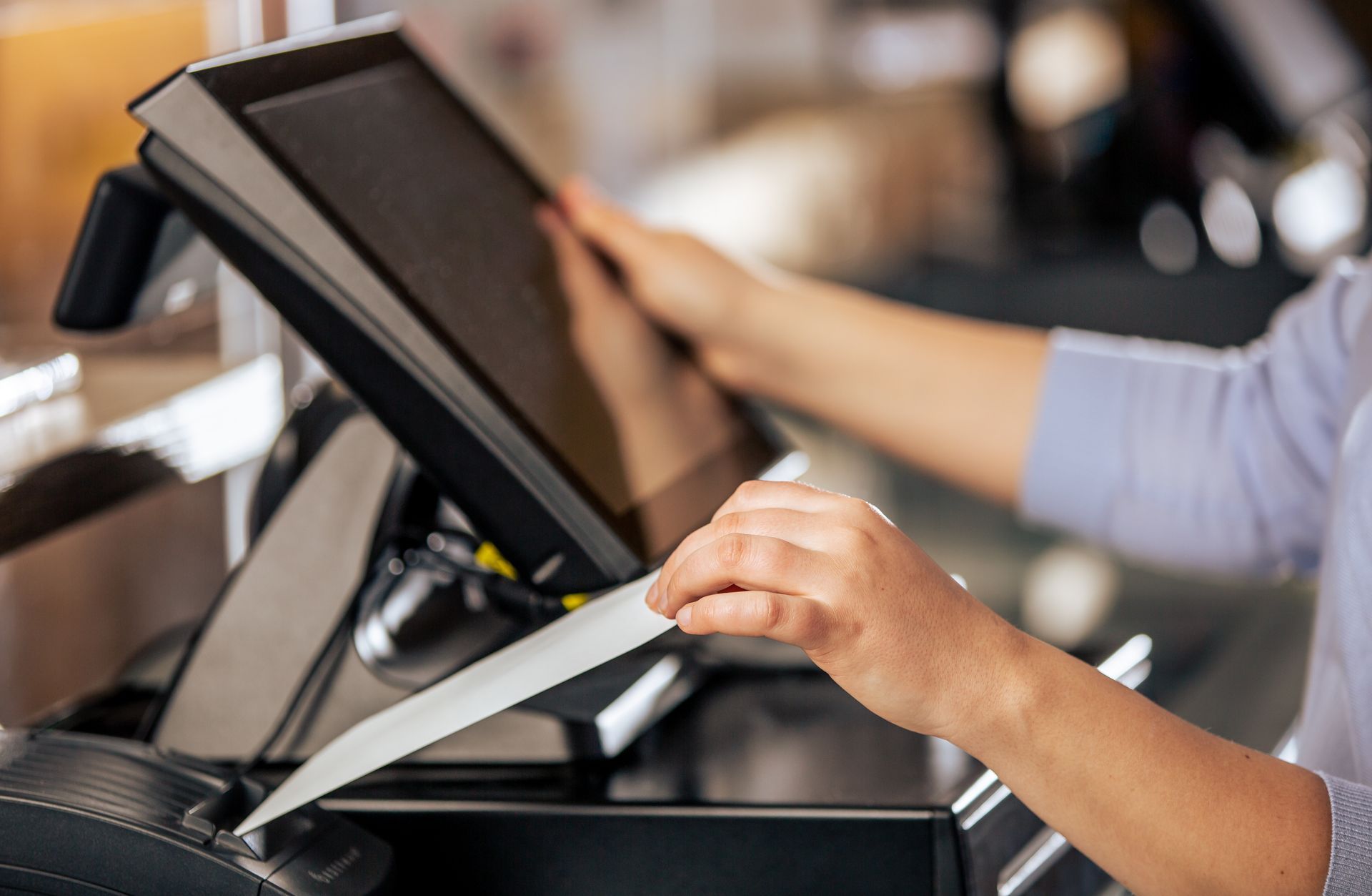Person holding a credit card near a touchscreen payment terminal at a checkout counter
