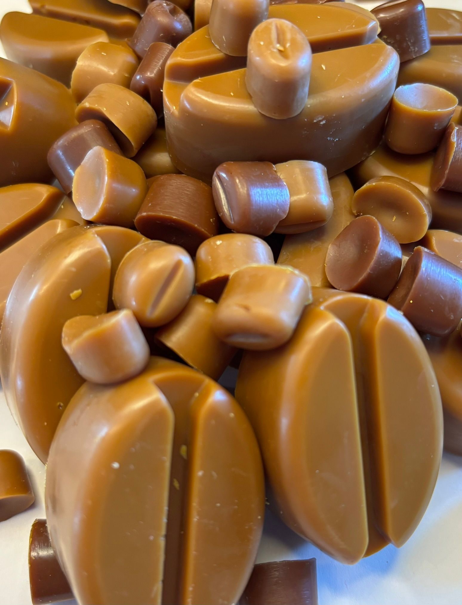 Een stapel koffieboonvormige  waxmelts op een effen witte achtergrond.