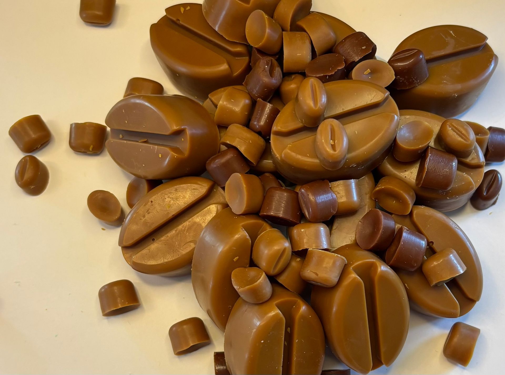 Een stapel koffieboonvormige  waxmelts op een effen witte achtergrond.