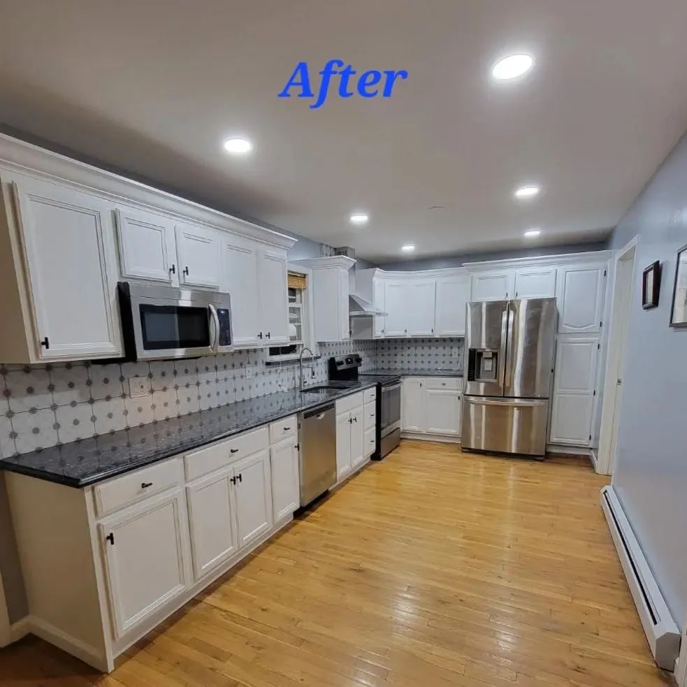 White kitchen cabinets and appliances, granite countertops, and wooden floors.
