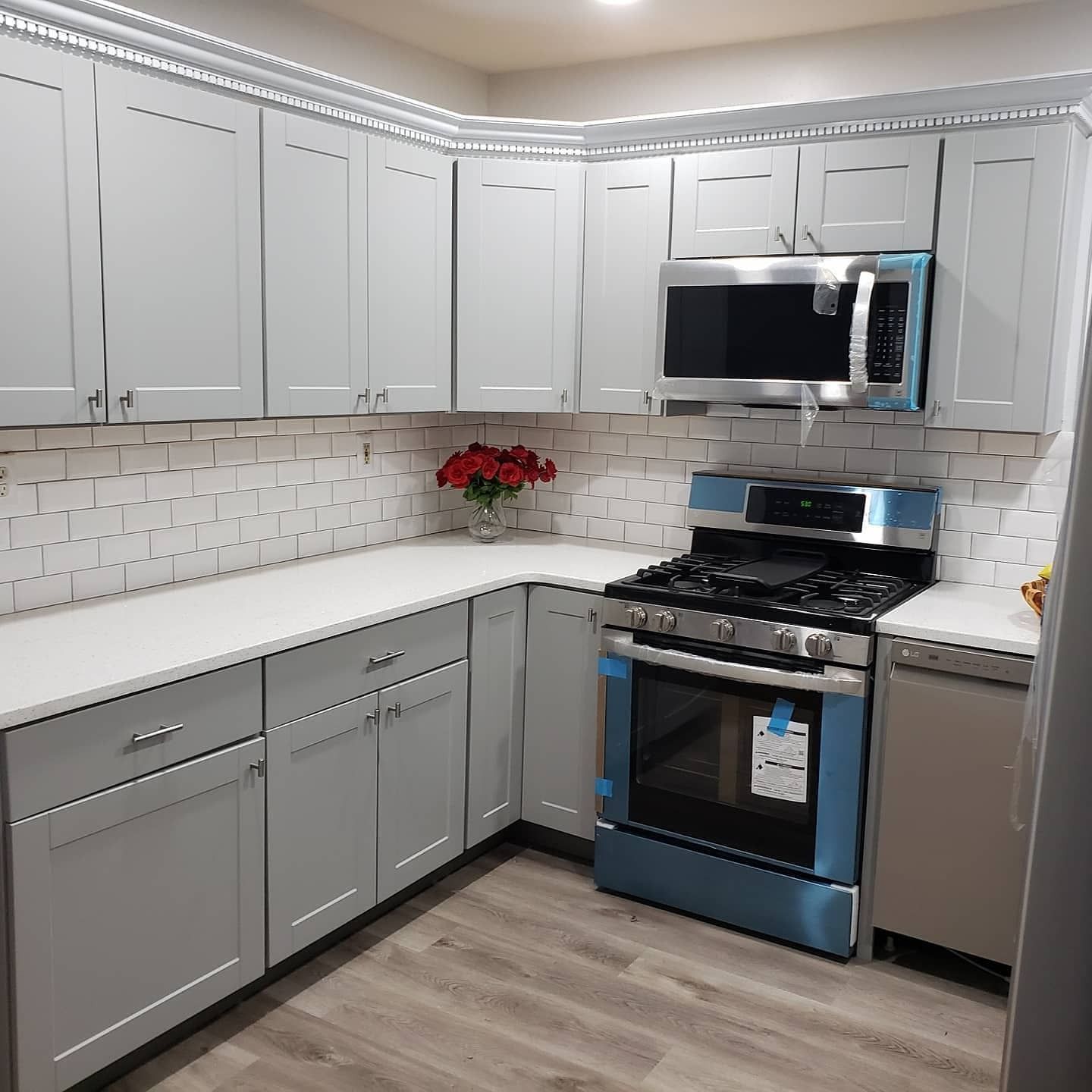 Light gray kitchen with matching cabinets, countertops, and tiled backsplash. Stainless steel appliances.