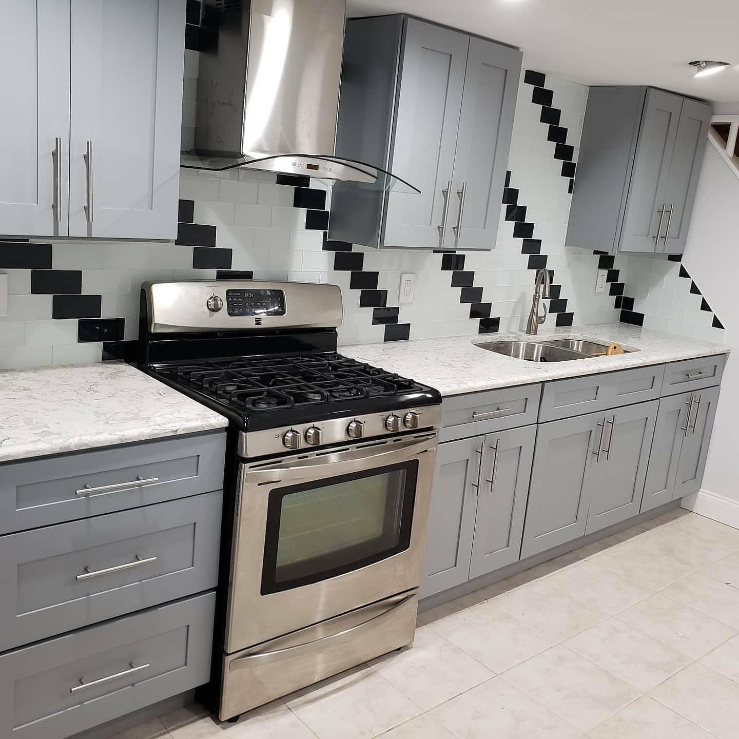 Gray and white kitchen with stainless steel appliances and a geometric backsplash.