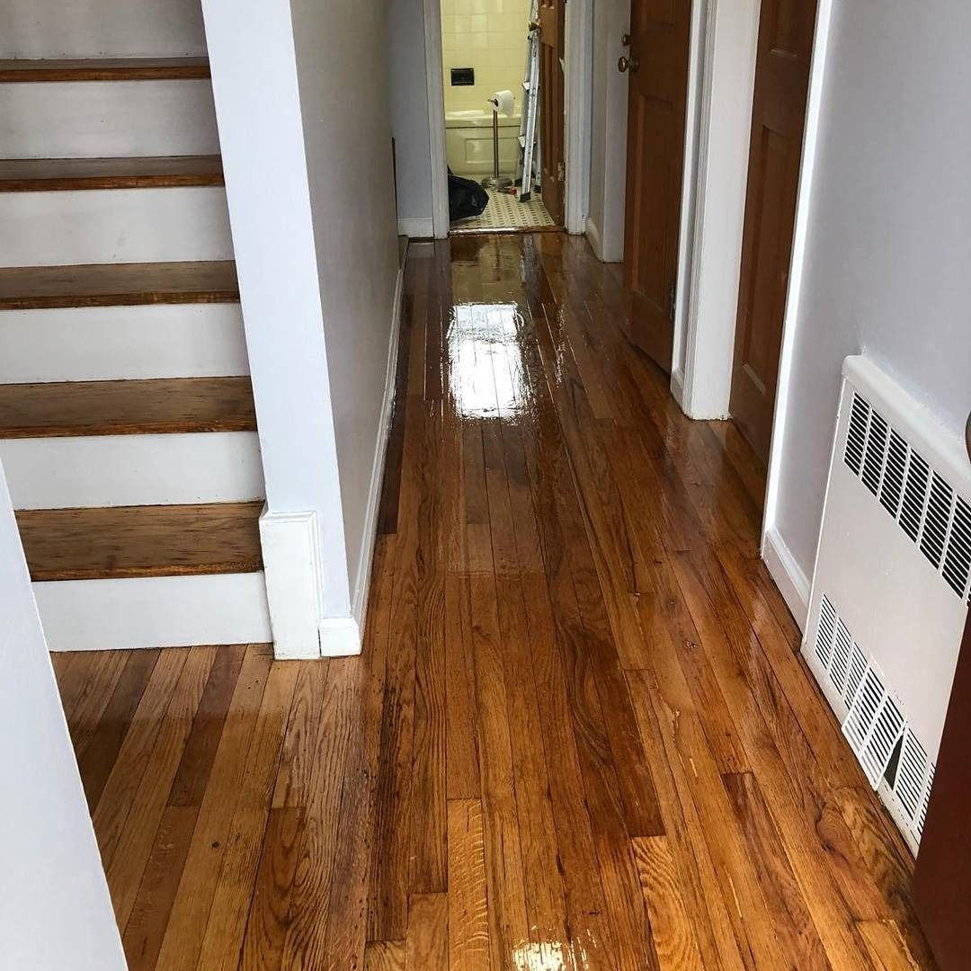 Hallway with shiny wooden floors, stairs on the left, and doors leading off on the right. A heater is on the wall.
