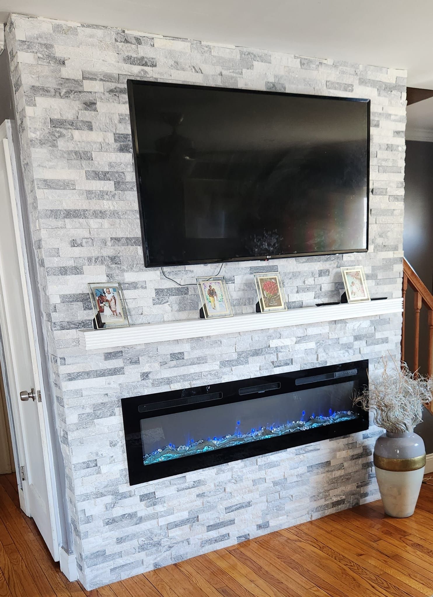 Fireplace with faux brick wall, TV, mantel with figurines, and an electric fireplace.
