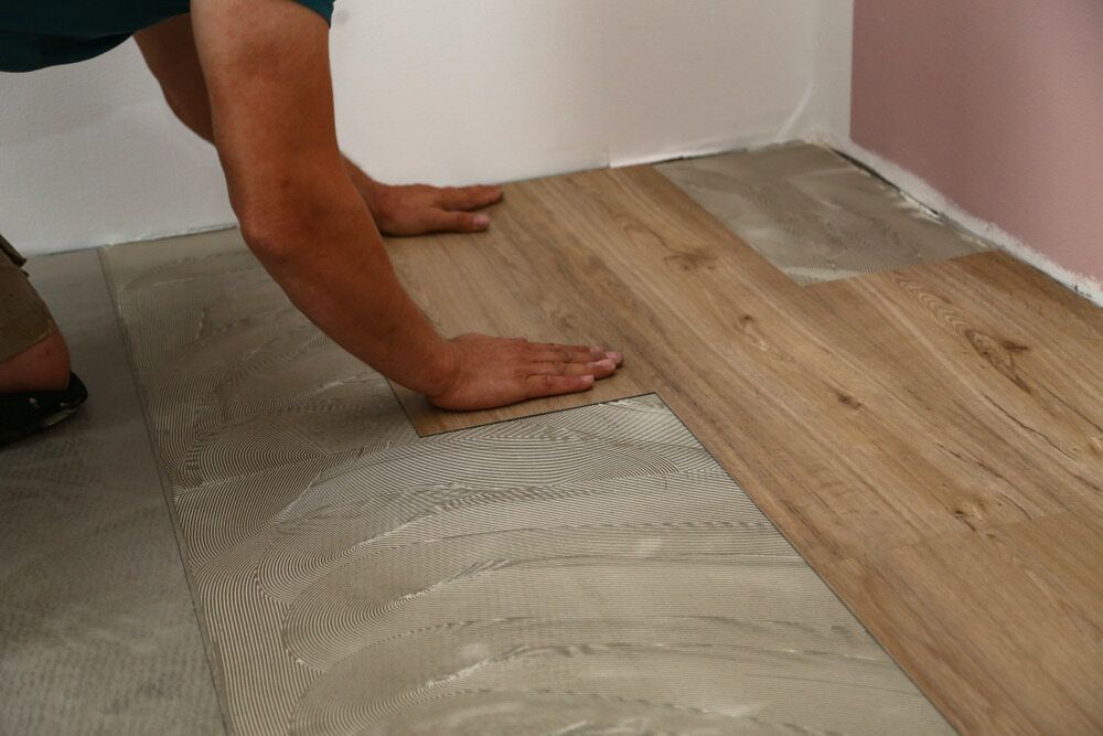 A Man is Installing a Wooden Floor in a Room — Taggerts Discount Carpets & Vinyls In California Gully, VIC