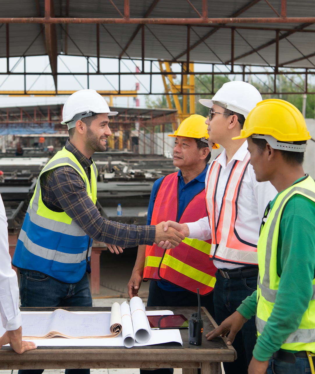 A group of construction workers are shaking hands at a table.