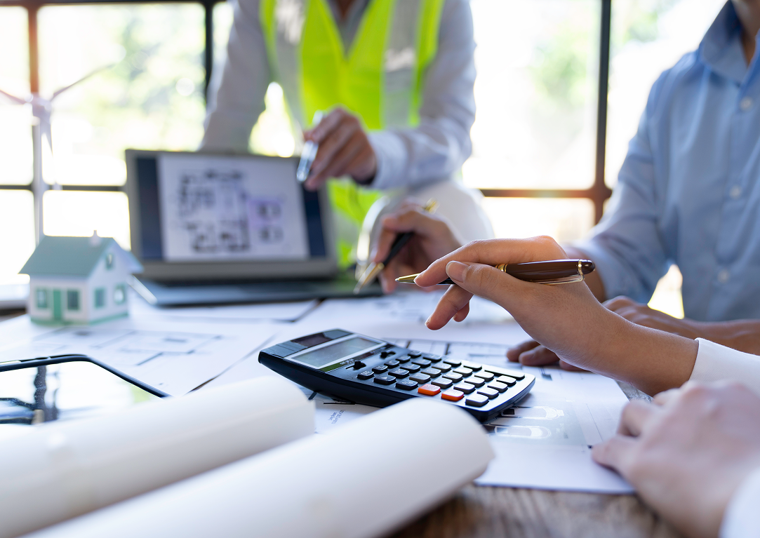 A group of people are sitting at a table with a calculator and a laptop.