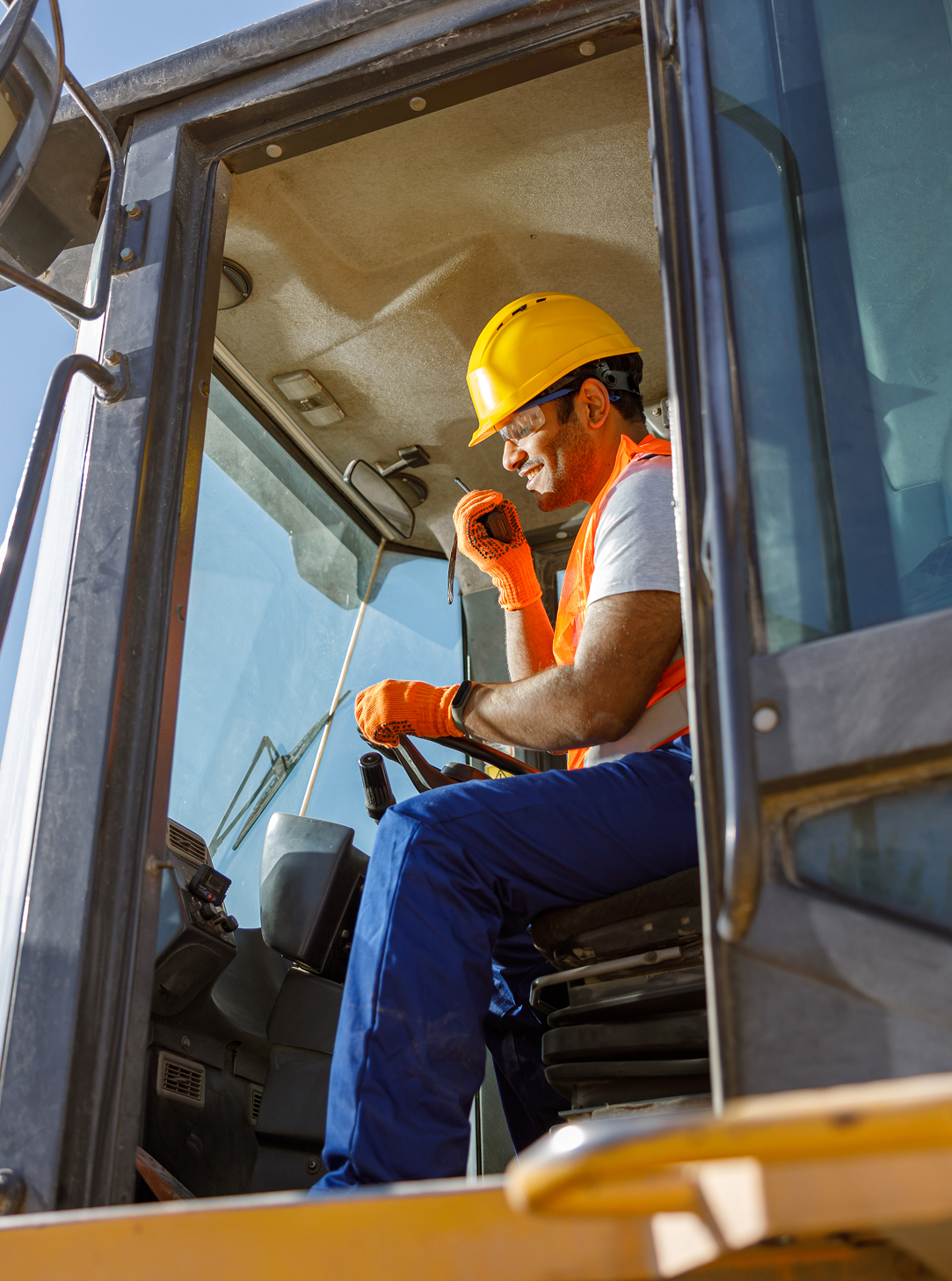 A man is sitting in the driver 's seat of a construction vehicle.