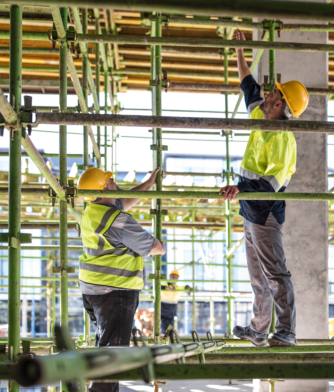 Two construction workers are working on scaffolding at a construction site.