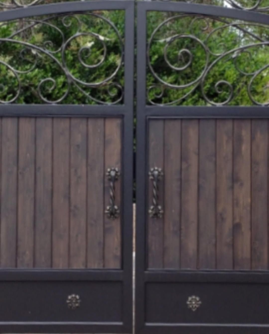 Dark wood gate with ornate wrought iron accents and handles.