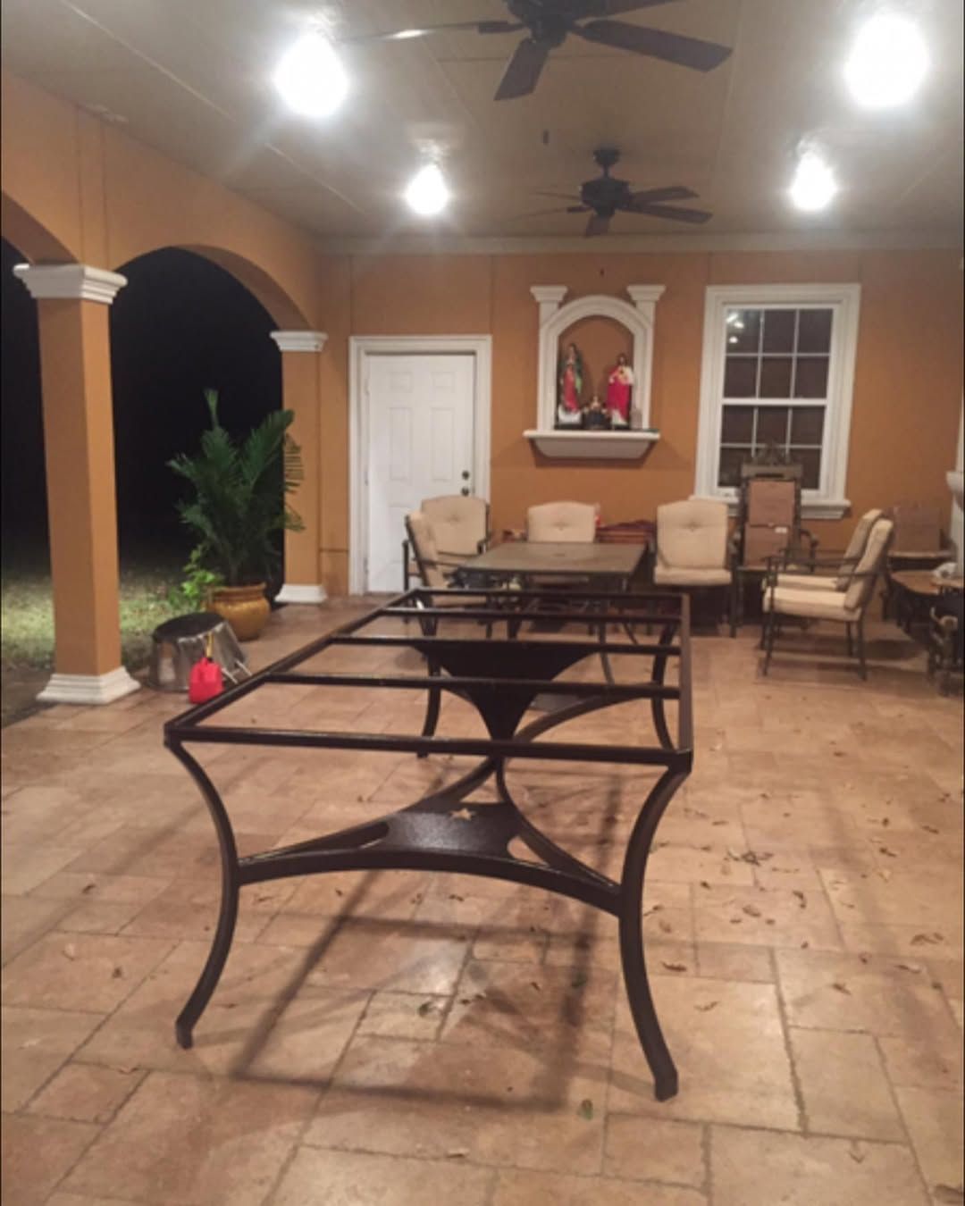 Metal table frame on a tiled patio, other furniture and architectural details.