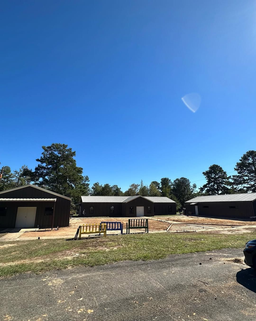 Brown buildings with white doors under a clear blue sky; a wooden bench in front.