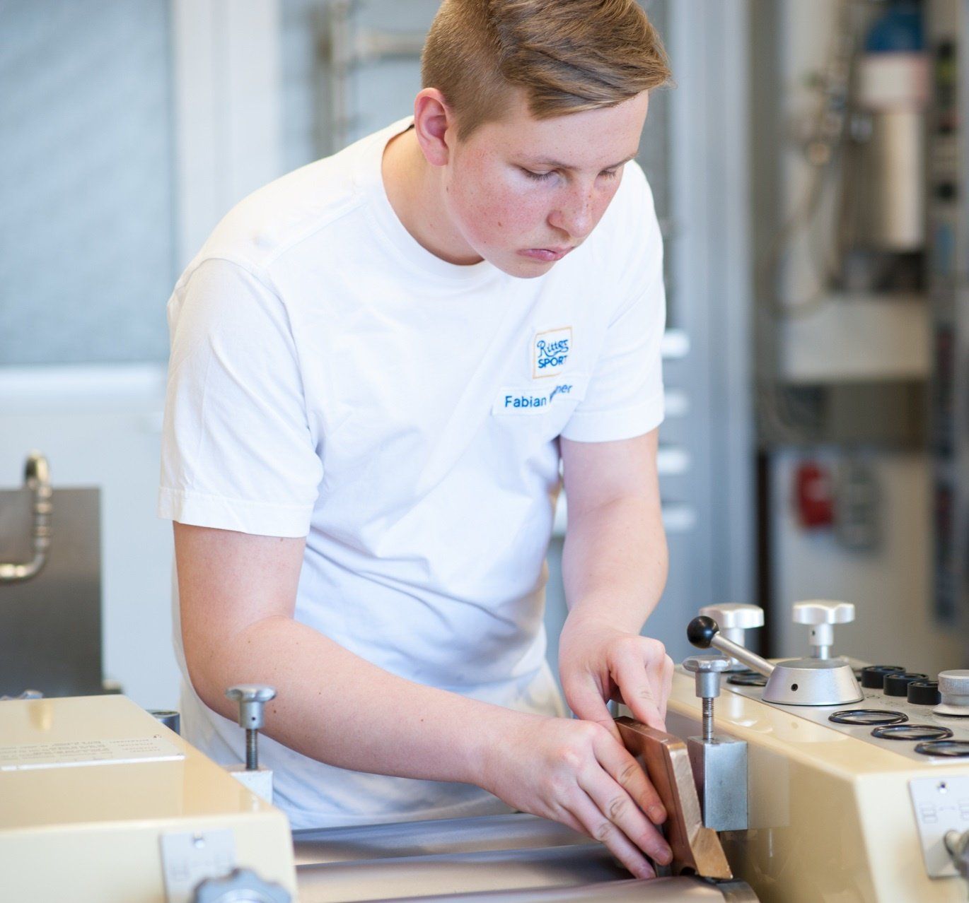 ein junger mann in einem weißen t-shirt arbeitet an einer maschine