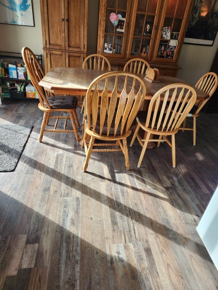 A wooden table and chairs are sitting on a wooden floor in a living room.