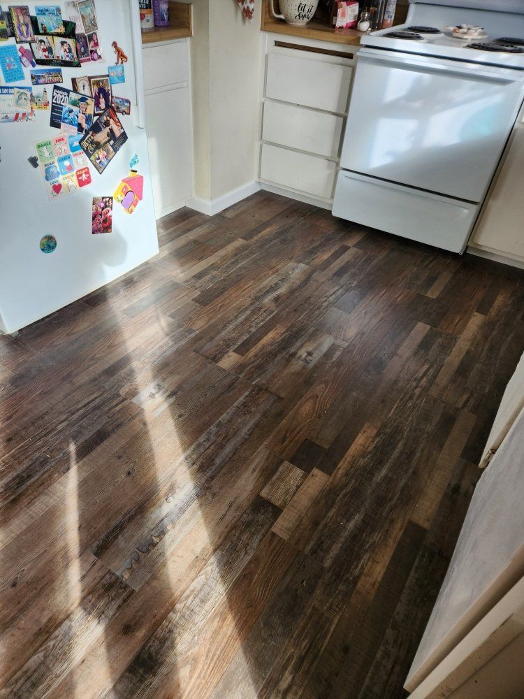 A kitchen with hardwood floors , a stove and a refrigerator.