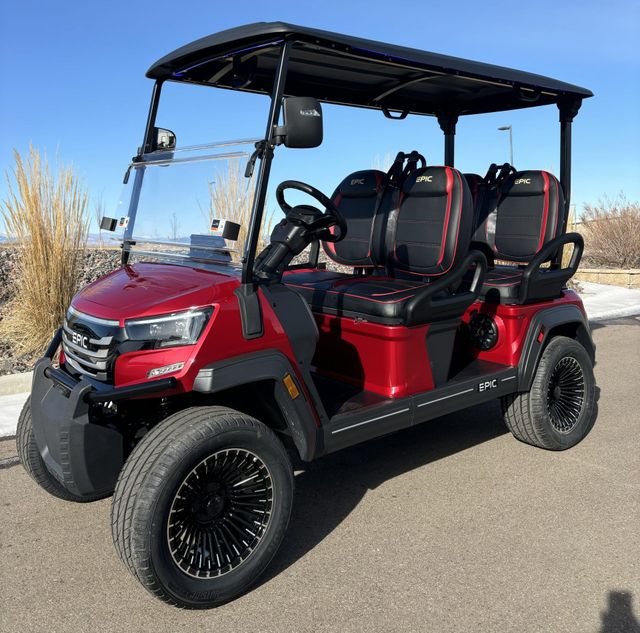 Red four-seat golf cart with black roof parked outdoors on a sunny paved road.