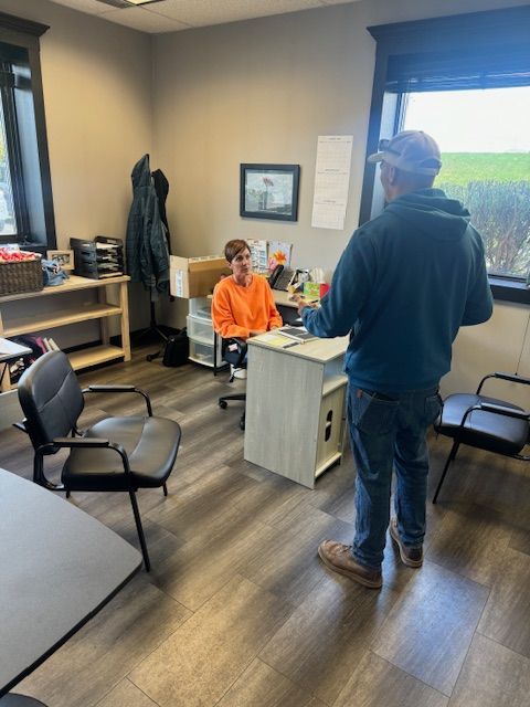 A man standing next to a woman sitting at a desk in an office