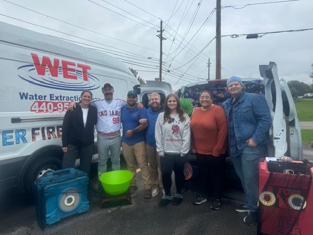 A group of people are posing for a picture in front of a wet van.