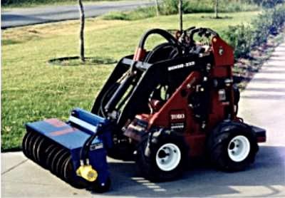 Red and black Toro compact utility loader with a blue sweeper attachment on a sidewalk.