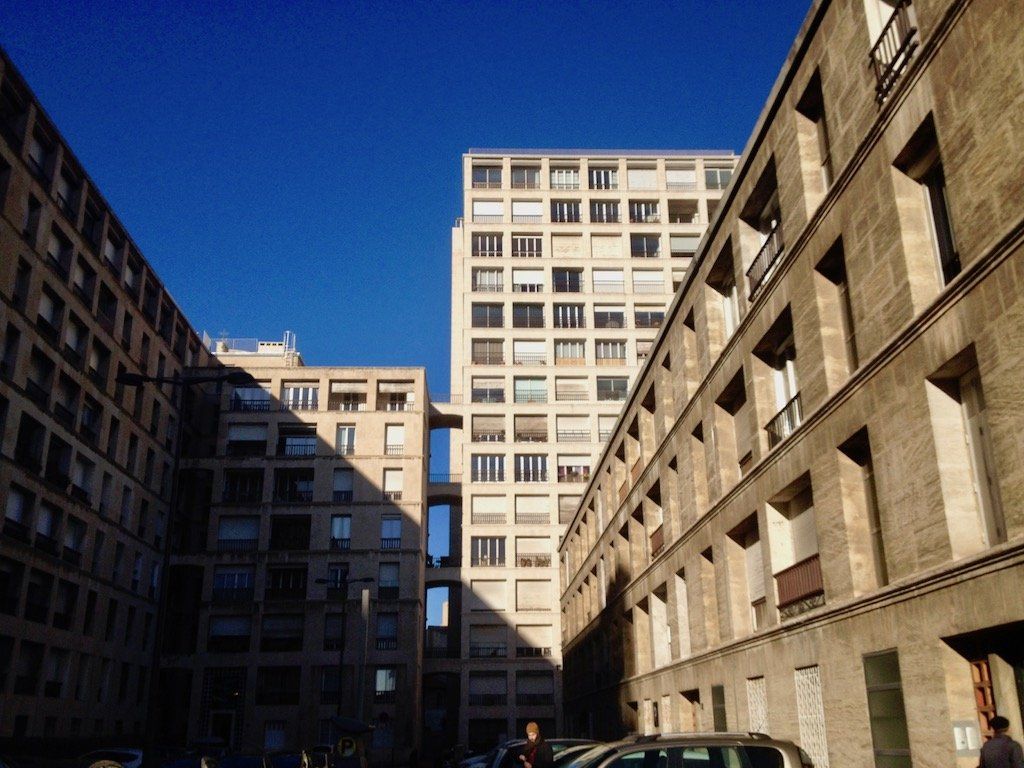 Sicht auf den Gebäudekomplex la Tourette von Fernand Pouillon, mehrere Blocks und ein Turm am Ende eines langen Hofes.