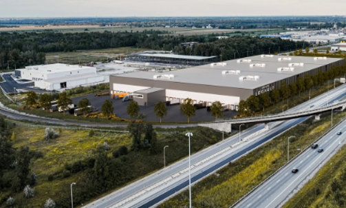 Une vue aérienne d'un grand entrepôt à côté d'une autoroute.