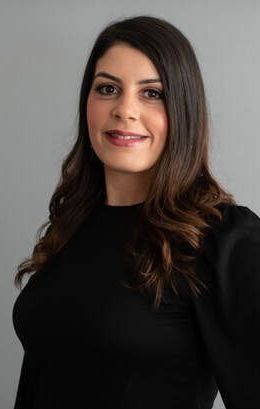 The woman is wearing a black sweater and smiling for the camera.