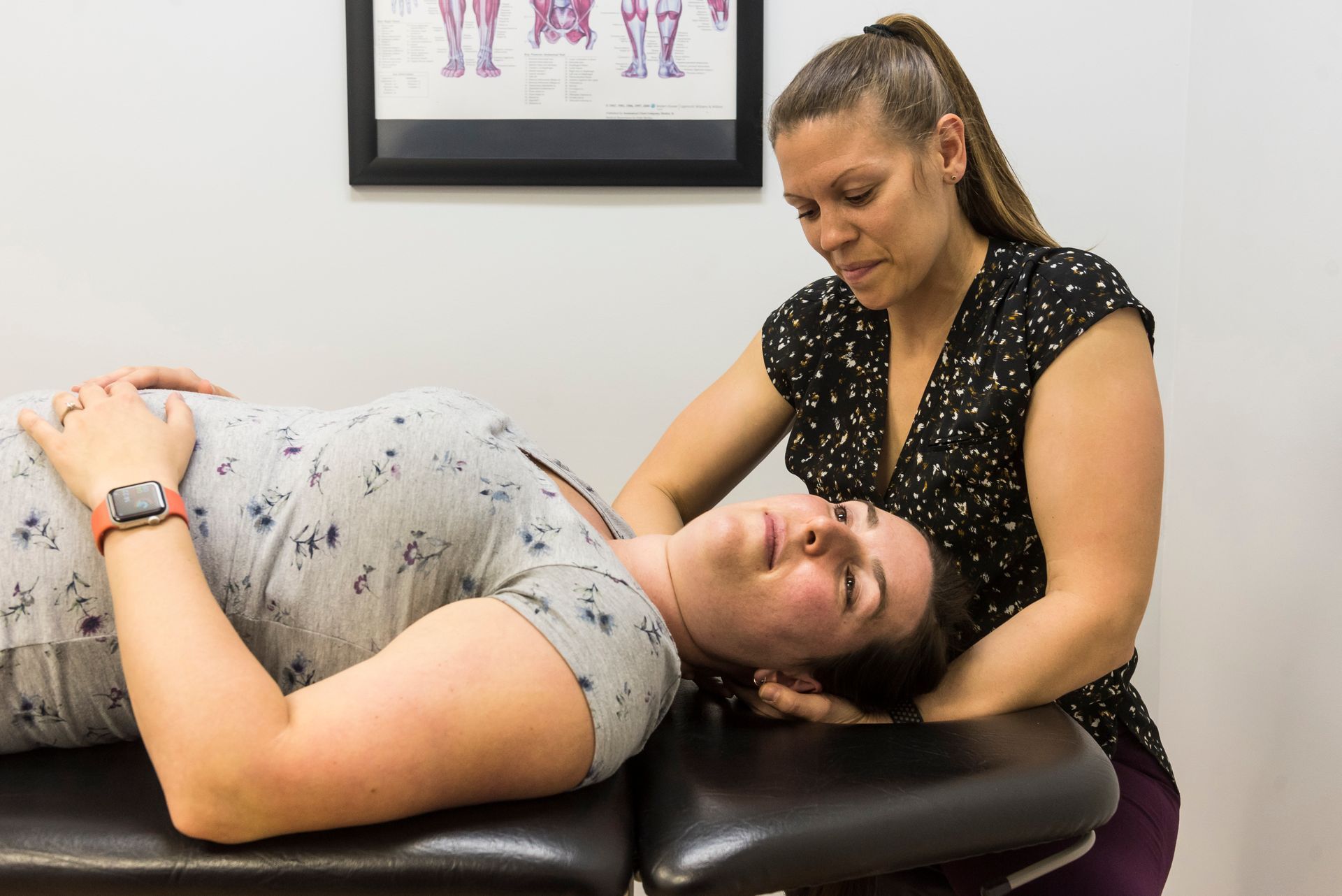 A woman is laying on a table getting a massage from another woman.