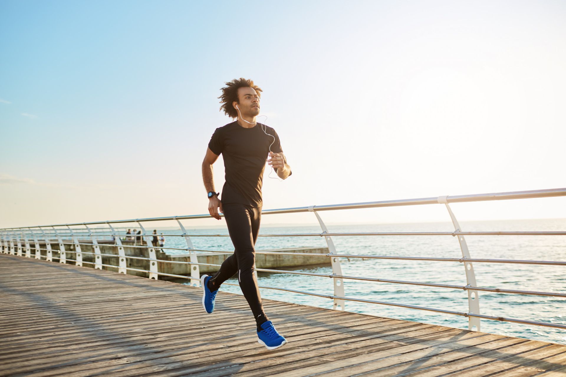 A man is running on a pier near the ocean.