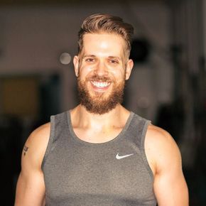 A man with a beard is wearing a grey nike tank top.