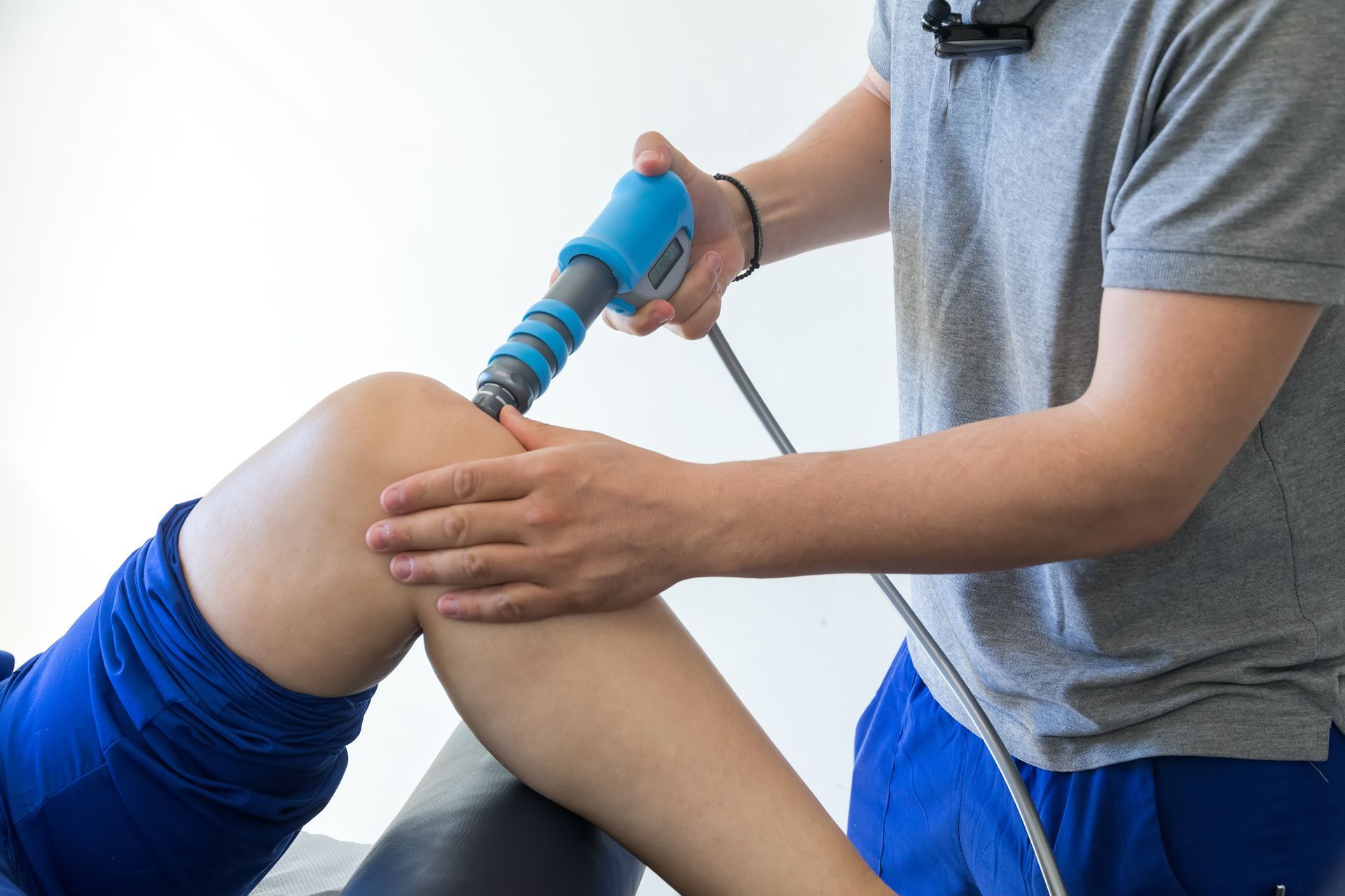 physiotherapist using shockwave therapy on patient