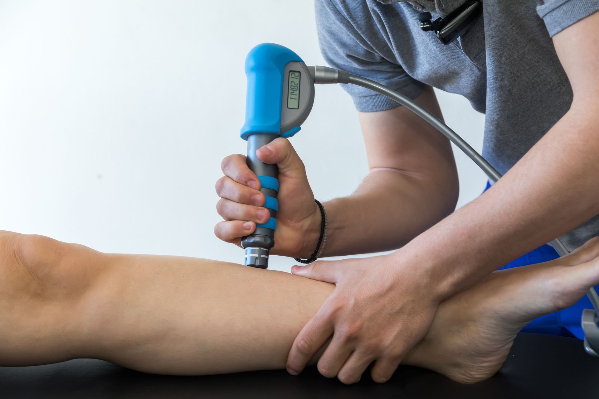 physiotherapist using shockwave therapy on patient's leg