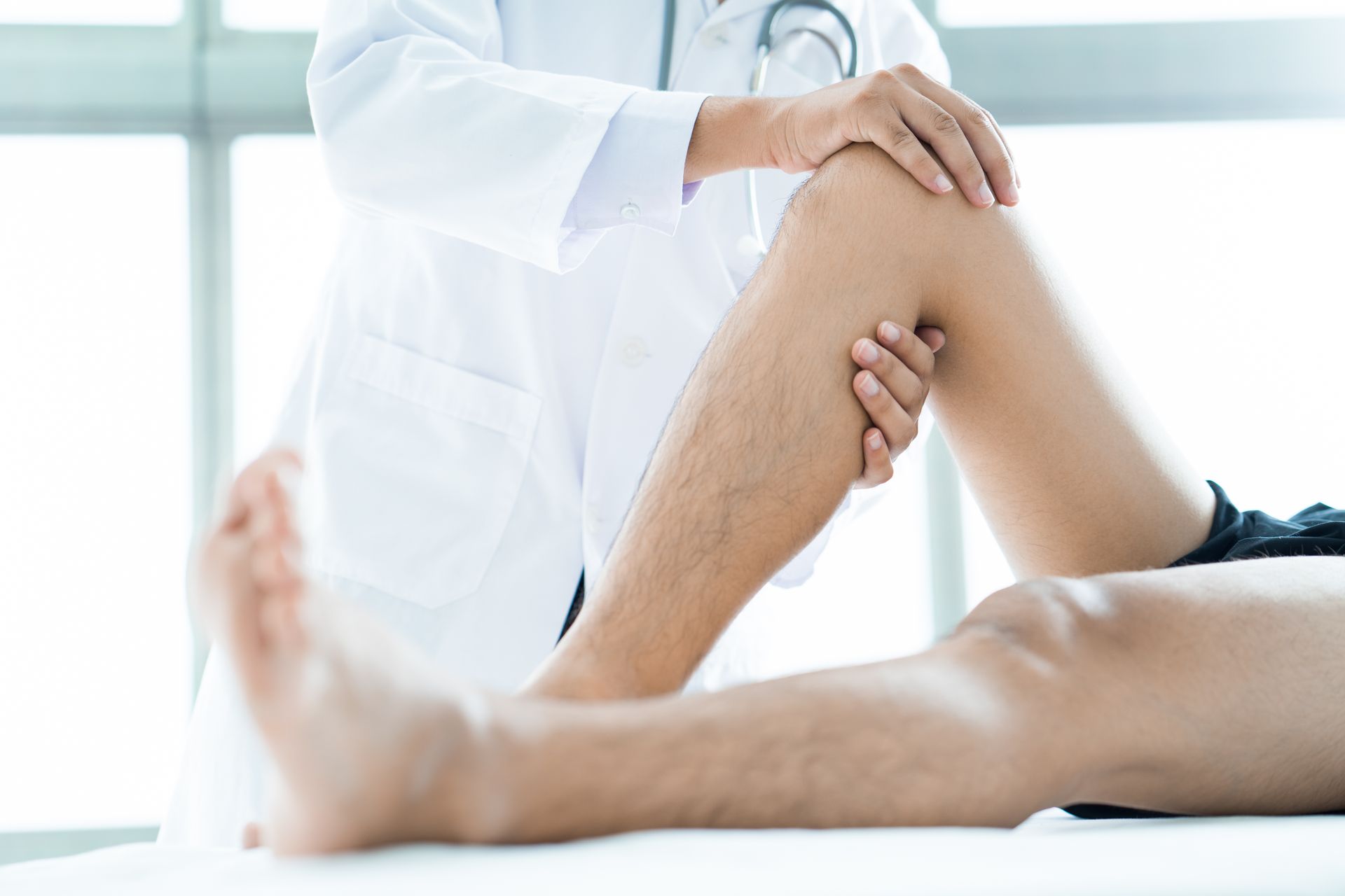physiotherapist massaging patient's knee treating orthopedic injury
