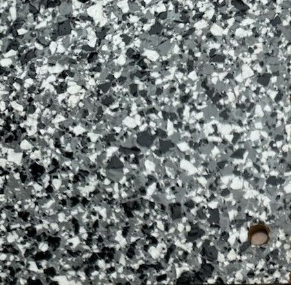 A close up of a marble texture with brown , white and black spots