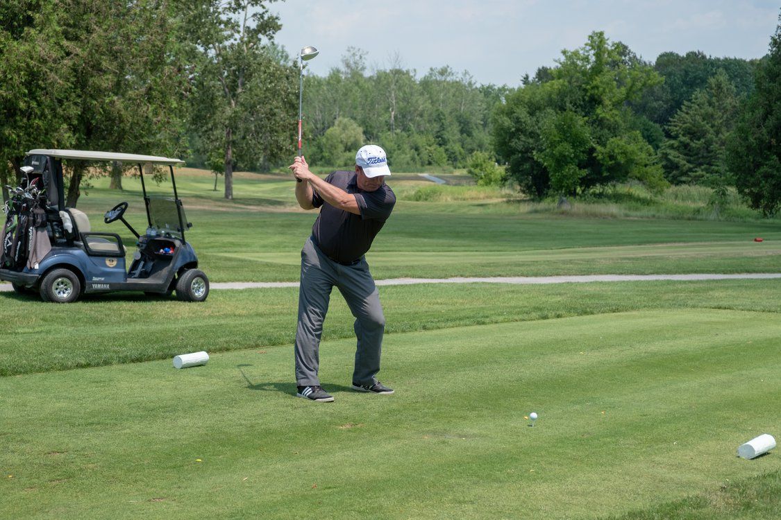 A man is swinging a golf club on a golf course.