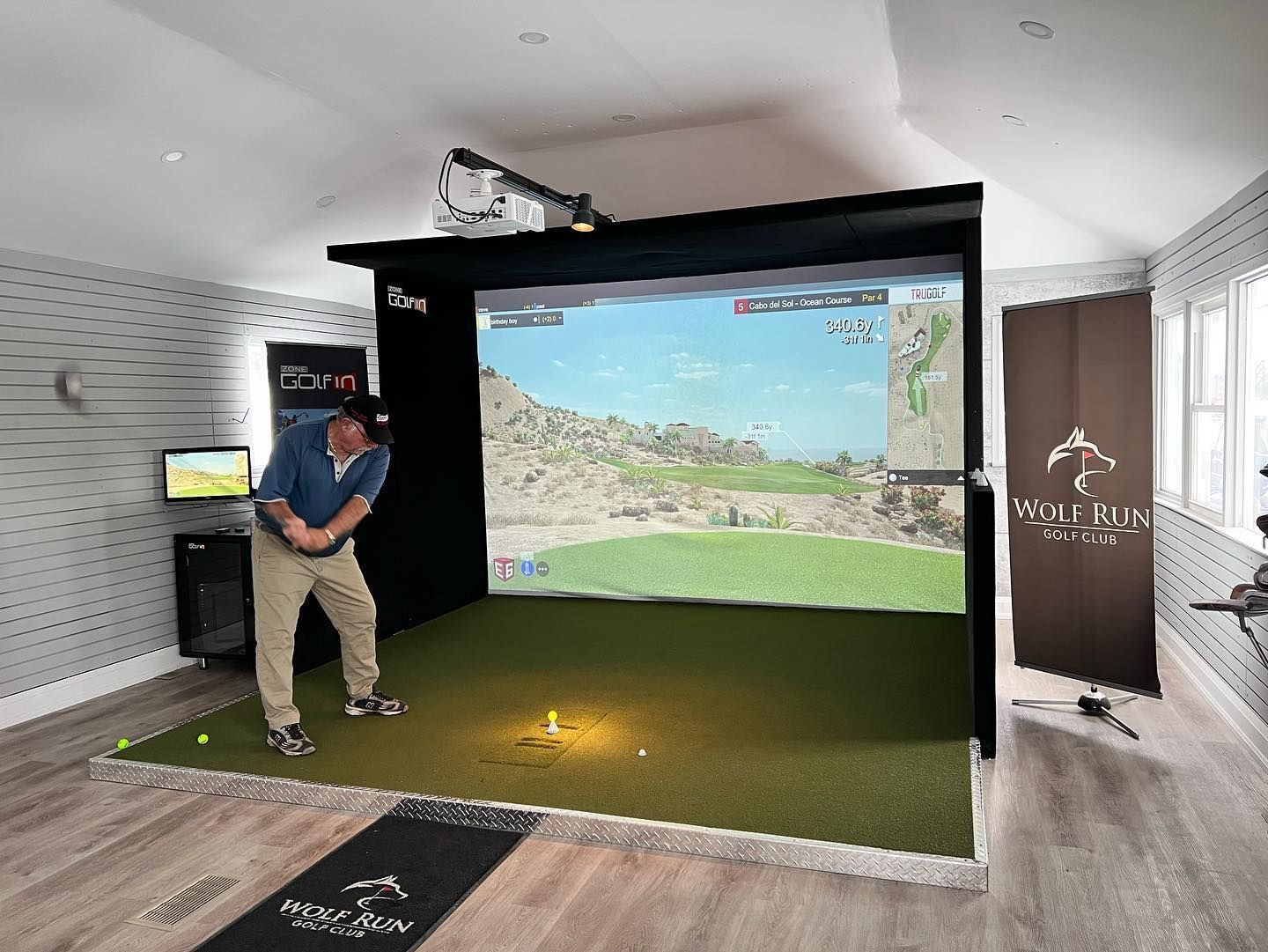 A man is swinging a golf club in a simulator.