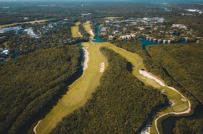 An aerial view of a golf course surrounded by trees and a river.