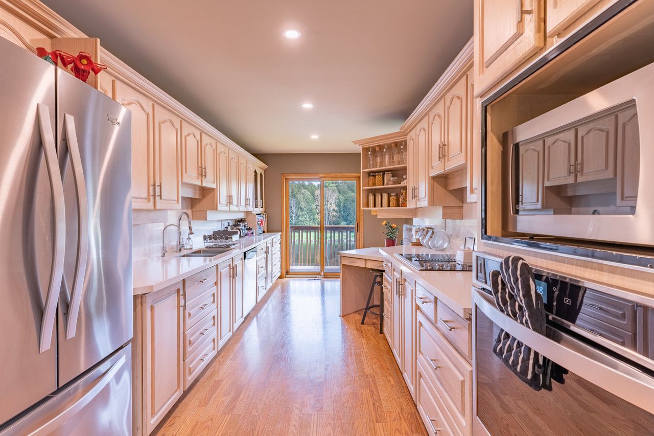 A long kitchen with stainless steel appliances and wooden cabinets.