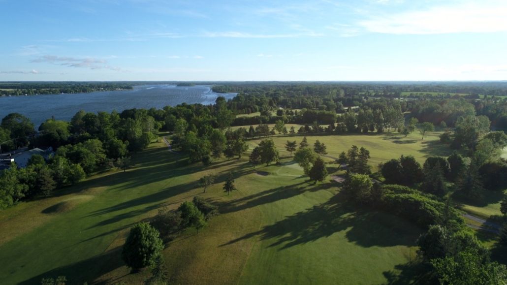 An aerial view of a golf course surrounded by trees and a lake.