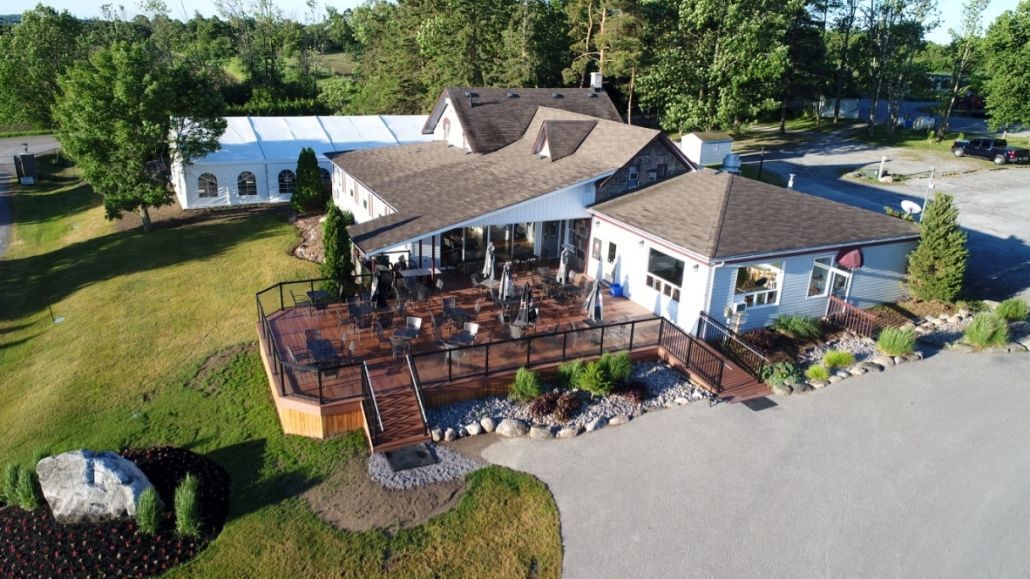 An aerial view of a large house with a large deck surrounded by trees.