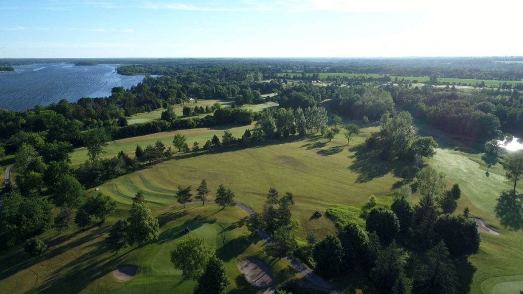 An aerial view of a golf course surrounded by trees and a lake.