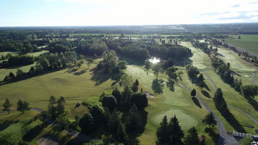 An aerial view of a golf course surrounded by trees and grass.